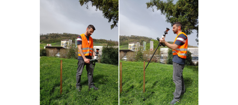 Surveyor with Leica AP20 AutoPole in grassy field, wearing orange safety vest.